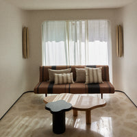 Modern living room featuring a brown striped sofa, neutral cushions, and light curtains with soft, natural tones.