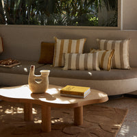 Beige and gold striped cushions on a light brown sofa, with a wooden coffee table and earthy tones in the decor.