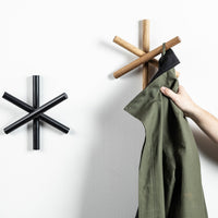 "Modern coat hooks in black and natural wood, featuring geometric star patterns on a white wall."