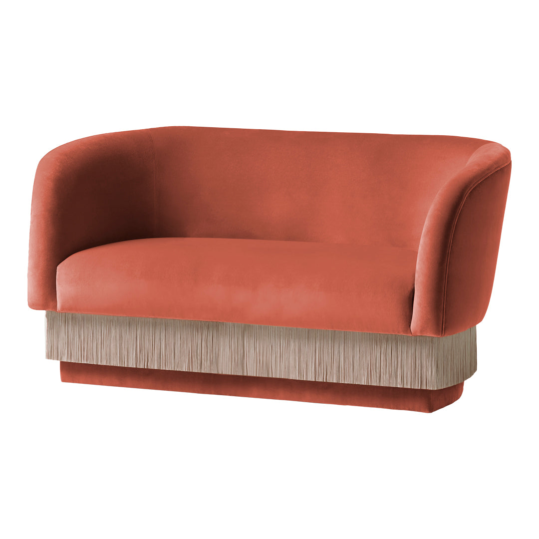 Coral velvet sofa with a textured beige fringe base, combining modern and elegant patterns for stylish decor.