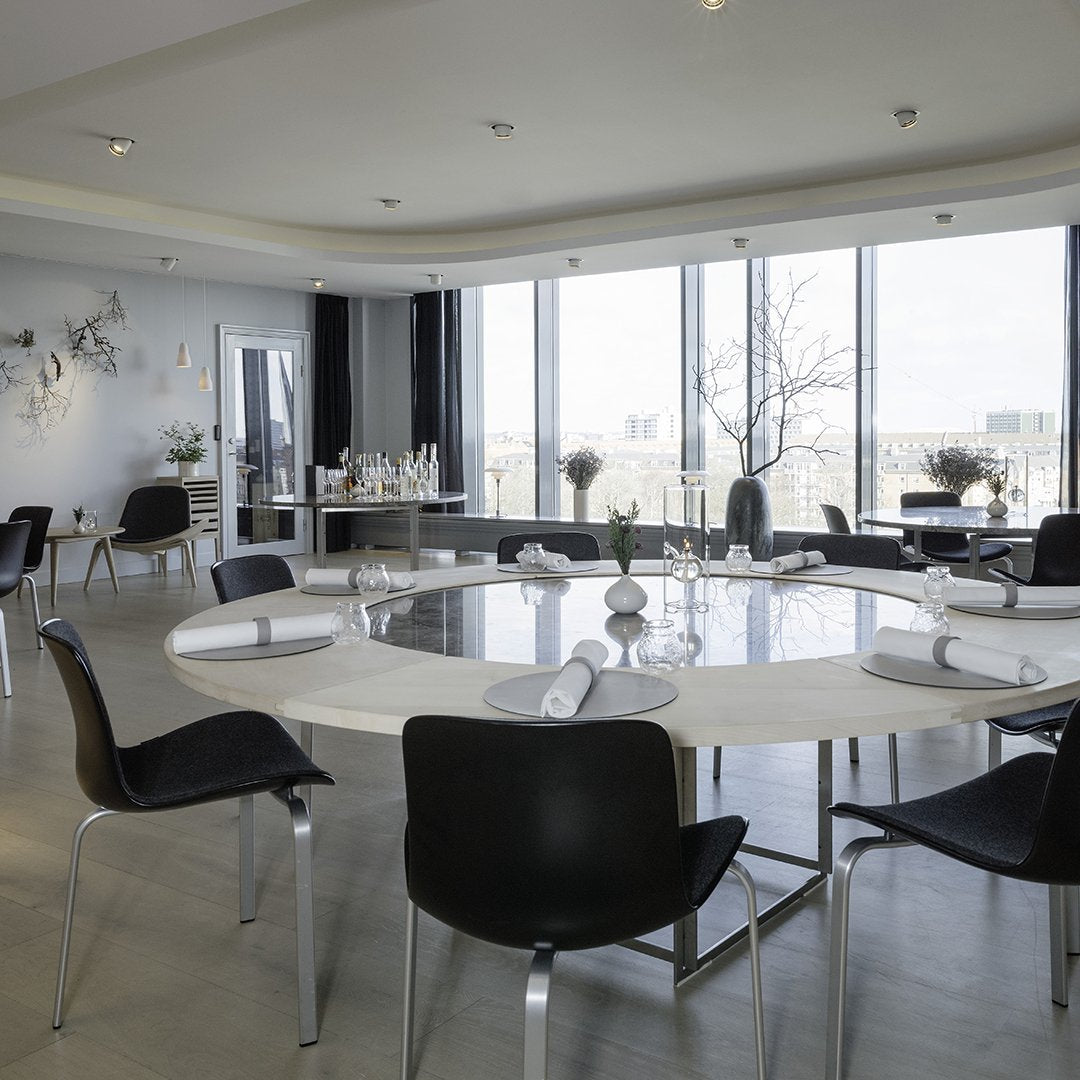 Modern dining room featuring a sleek round table, black chairs, and neutral tones with elegant, minimalist decor.