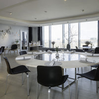 Modern dining room featuring a sleek round table, black chairs, and neutral tones with elegant, minimalist decor.
