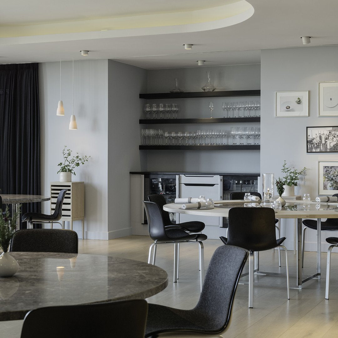 Modern dining room featuring gray walls, black chairs, and marble tables with subtle decor accents.