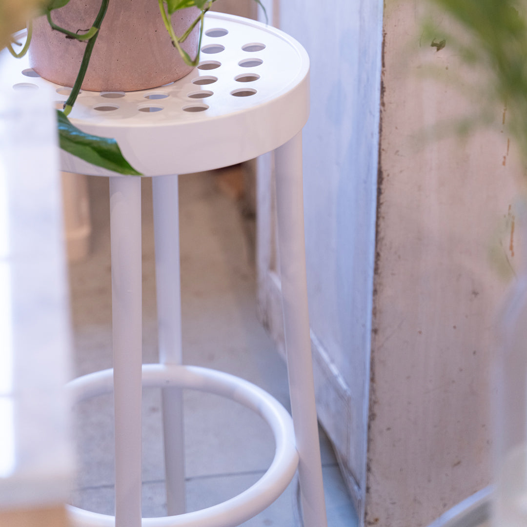 White stool featuring a circular patterned seat and sleek legs, accentuating a modern, minimalist aesthetic.