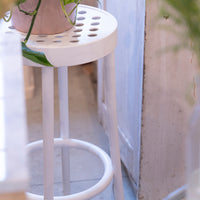 White stool featuring a circular patterned seat and sleek legs, accentuating a modern, minimalist aesthetic.