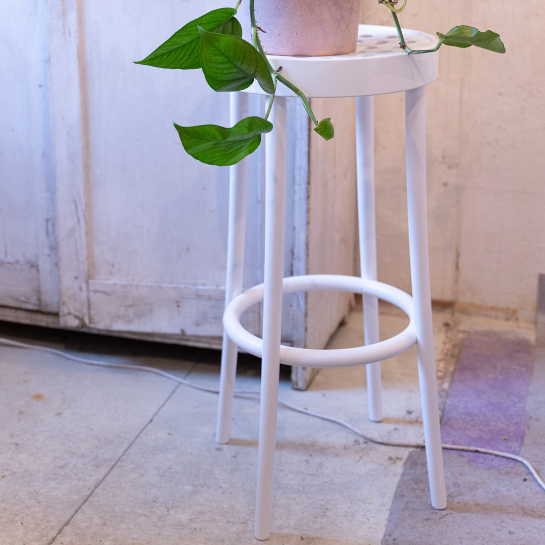 White stool with a minimalist design, featuring clean lines and a circular seat, perfect for modern decor.