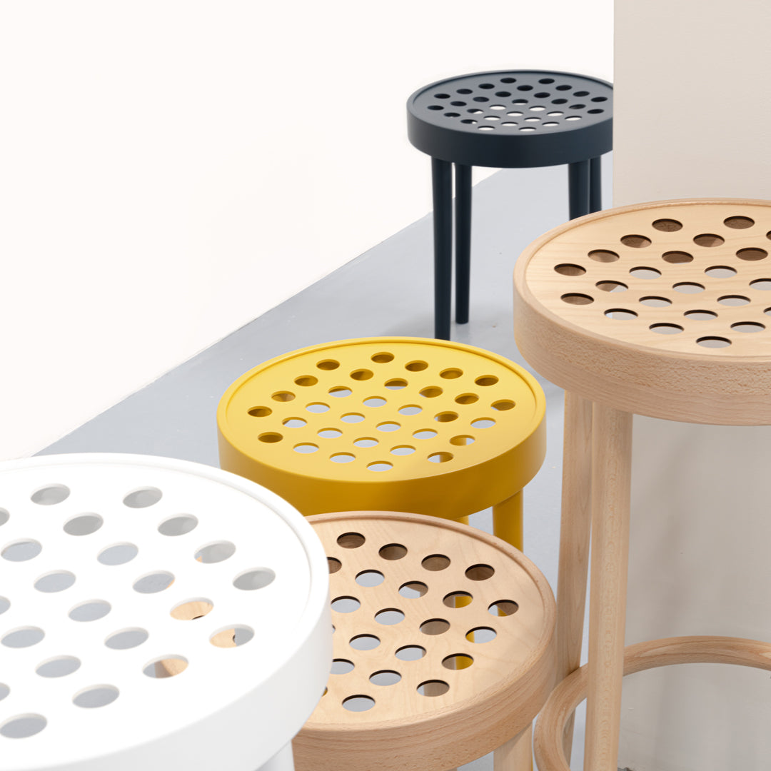 Colorful stools featuring white, yellow, and black finishes with unique perforated patterns for modern decor.