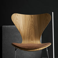Natural wood chair with a light oak finish and a curved back, complemented by a dark brown leather seat.