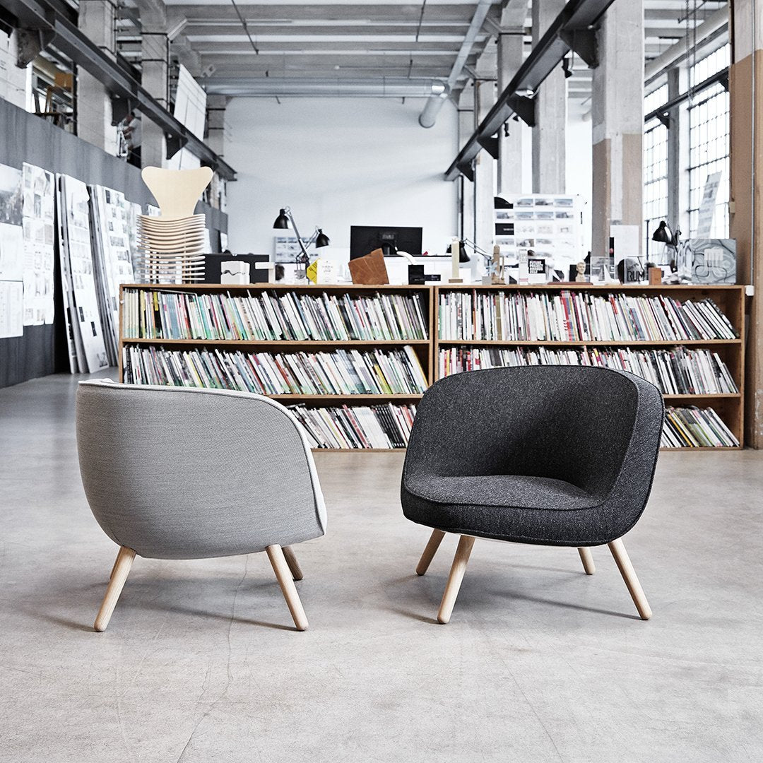 Modern chairs in gray and black upholstery with light wooden legs, featuring smooth, curved designs.