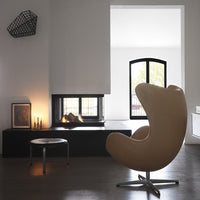 Beige curved chair with sleek lines, paired with black accents and a minimalistic decor style in a modern interior setting.