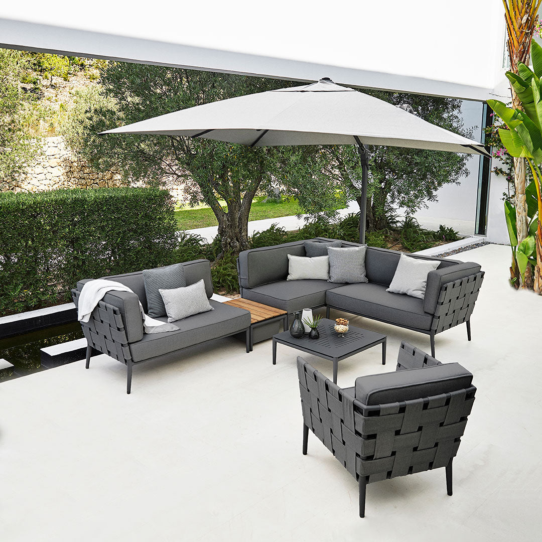 Modern outdoor seating set featuring sleek gray cushions and a light gray umbrella, with geometric patterns.