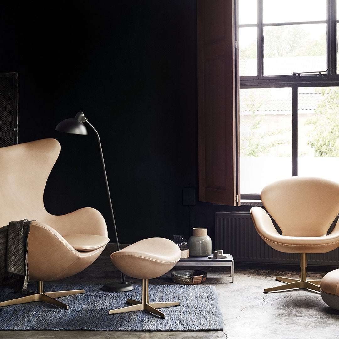 Elegant cream chairs with sleek gold bases, set against a dark backdrop and a textured blue rug.