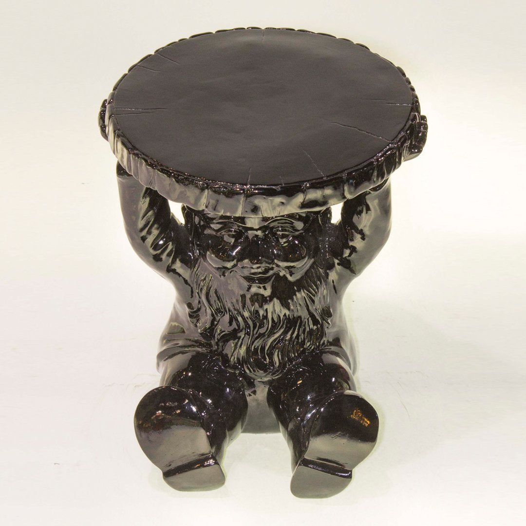 Black ceramic gnome stool with a glossy finish and a smooth round top, adding a whimsical touch to decor.