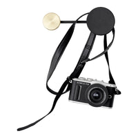 Black camera strap with round black and gold accents, featuring a sleek design perfect for photography enthusiasts.