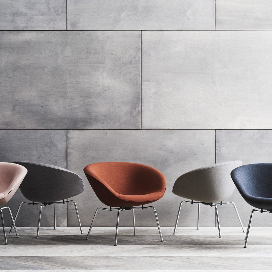 Colorful modern chairs in shades of pink, gray, orange, and navy against a sleek gray wall. Stylish and contemporary design.
