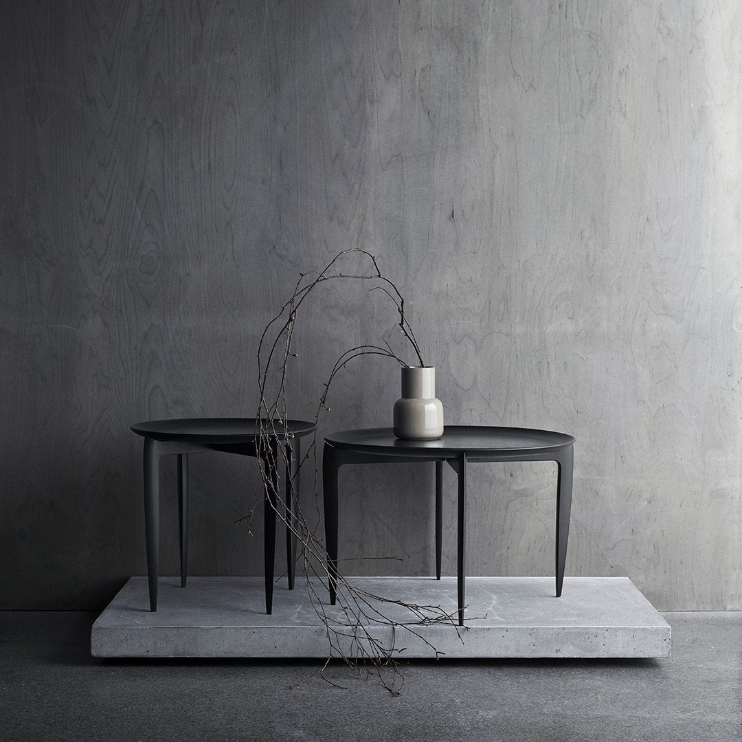 "Two sleek black side tables on a light gray concrete base, showcasing minimalist design and modern aesthetics."