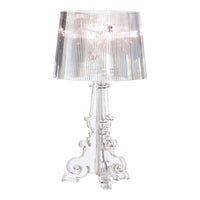 Clear acrylic lamp with a textured shade illuminating a warm, cozy ambiance. Blinds create soft shadow patterns.