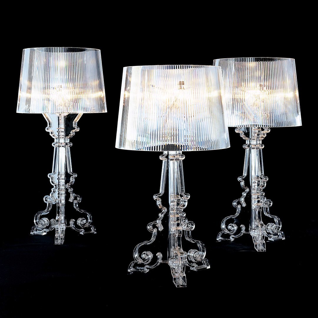 Elegant crystal table lamp with a transparent shade, casting warm golden light against a dark outdoor setting.