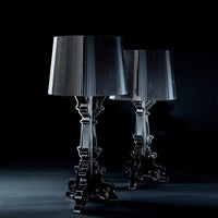 Two elegant black lamps with pleated grey shades, set against a dark backdrop, showcasing sleek lines and sophisticated design.