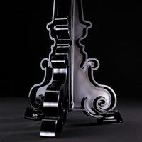 Glossy black stand with intricate scrollwork and curvy patterns against a dark background.