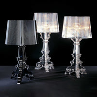 Three stylish lamps: one black, one transparent, and one iridescent, featuring elegant bases with intricate patterns.