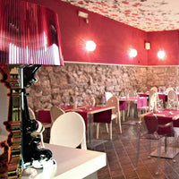Elegant dining room featuring burgundy walls, patterned ceiling, and mix of white and red chairs. Modern ambiance design.