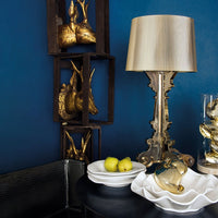 Gold accents on a deep blue wall, featuring white ceramics and a striped lamp shade for a chic, modern decor.
