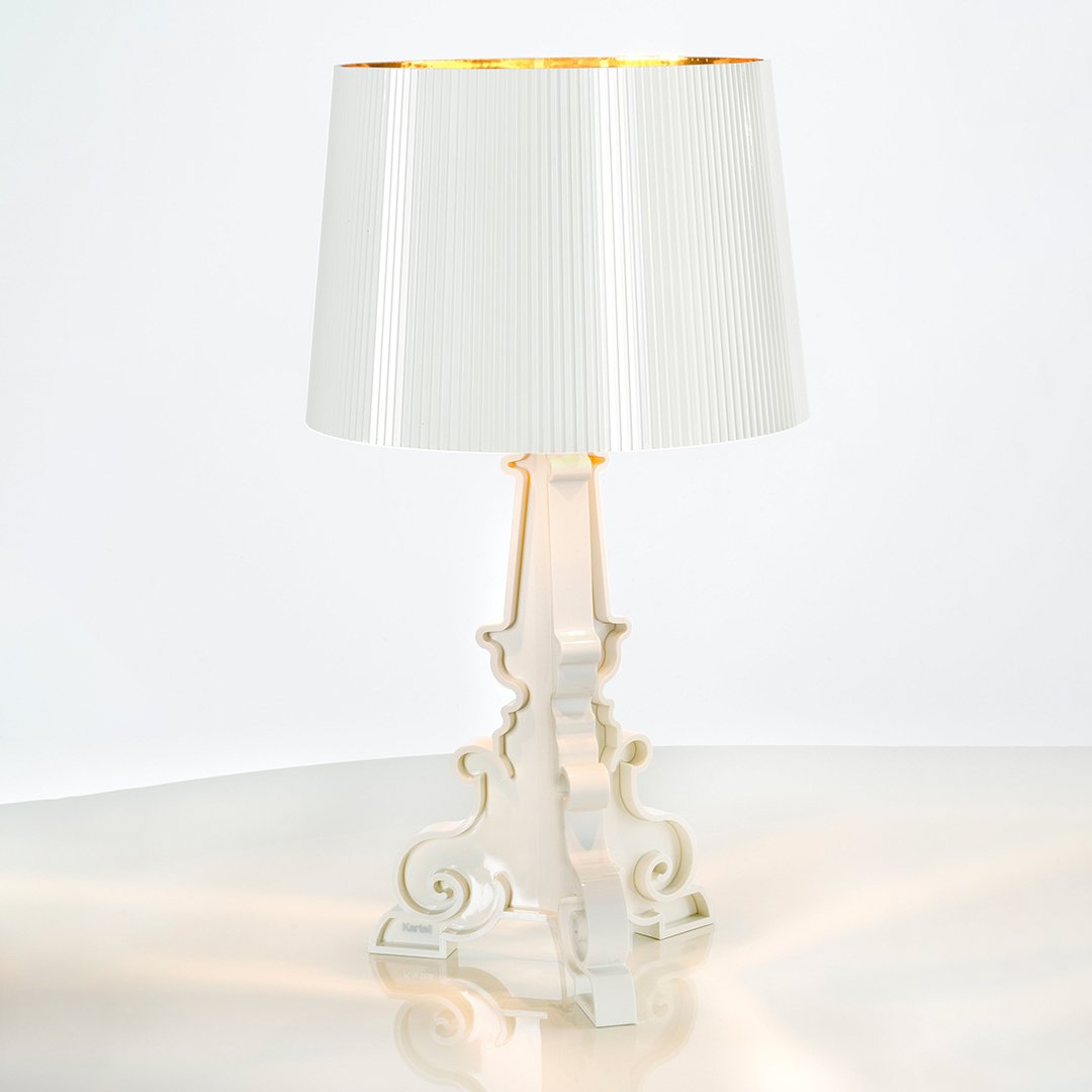 White lamp with a pleated shade and gold interior, featuring an elegant, ornate base design. Stylish and modern decor.