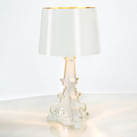 White lamp with a pleated shade and gold interior, featuring an elegant, ornate base design. Stylish and modern decor.