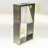 Sleek silver metal lamp with a textured, striped lampshade, featuring a modern design and geometric patterns.