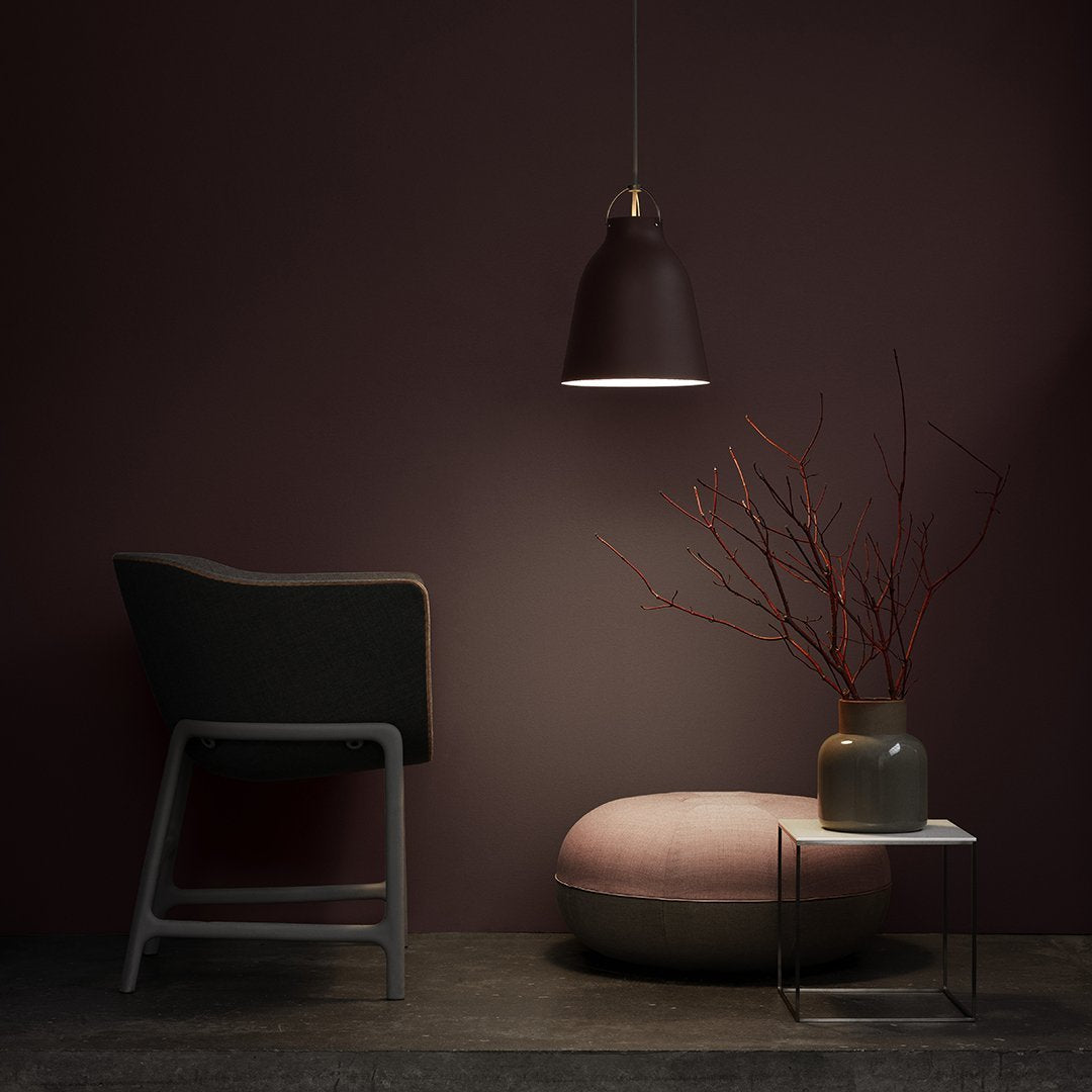 Modern chair and pendant lamp in deep purple tones, pink pouf, and minimalistic decor with neutral gray and beige accents.