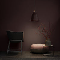 Modern chair and pendant lamp in deep purple tones, pink pouf, and minimalistic decor with neutral gray and beige accents.