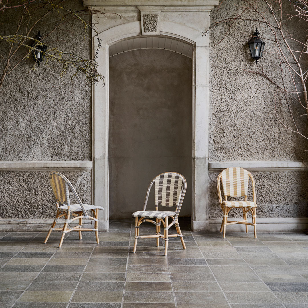 Three stylish chairs featuring beige stripes and patterns, set against a textured gray wall. Perfect for elegant spaces.