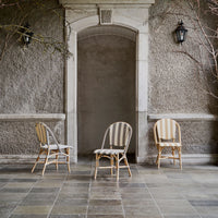 Three stylish chairs featuring beige stripes and patterns, set against a textured gray wall. Perfect for elegant spaces.