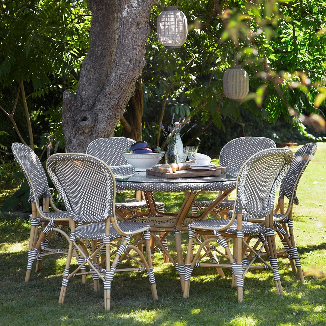 "Elegant outdoor dining set with grey woven chairs and a round wooden table, complemented by natural bamboo accents."