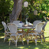 "Elegant outdoor dining set with grey woven chairs and a round wooden table, complemented by natural bamboo accents."