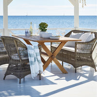 Coastal dining set featuring gray wicker chairs, a natural wood table, and white-blue striped accents. Perfect for outdoor spaces.