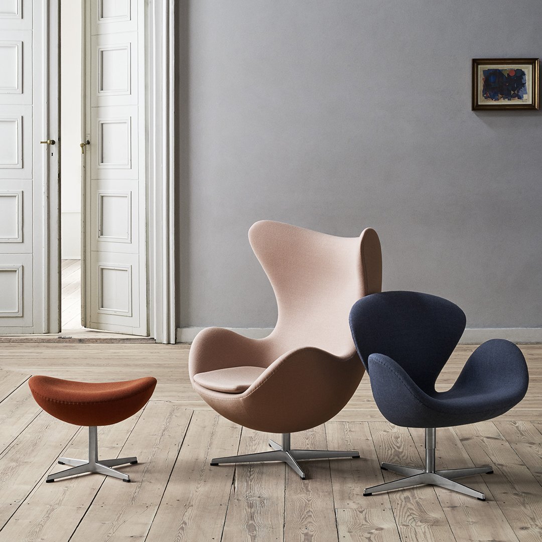 "Modern chairs in soft pink, deep navy, and warm brown with smooth curves, set against a minimalist interior."