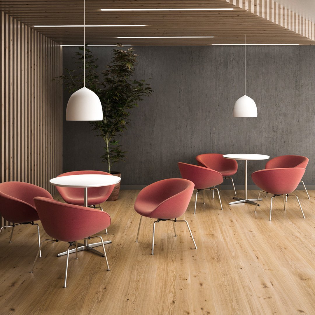 Modern seating in soft pink, paired with a white table, against a gray wall and warm wooden floor. Elegant design contrast.