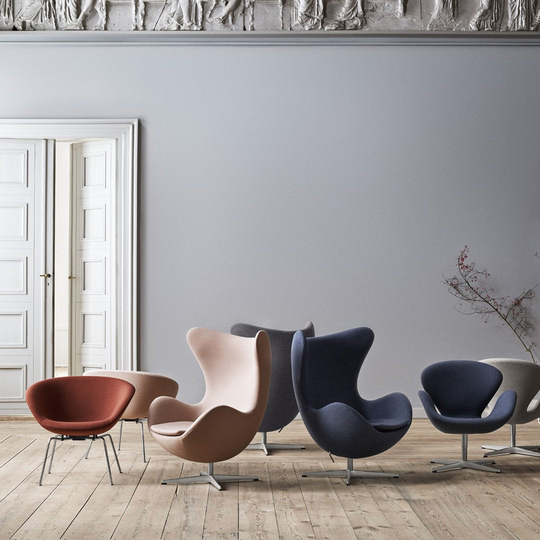 "Collection of stylish chairs in shades of red, pink, gray, and blue against a soft gray wall."