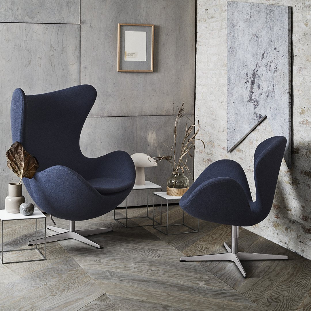 Pair of modern chairs featuring a deep navy blue fabric with sleek, minimalist design against a textured neutral backdrop.
