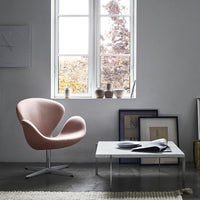 Pink modern chair with a sleek design, white coffee table, and neutral room decor. Minimalist patterns and soft colors.