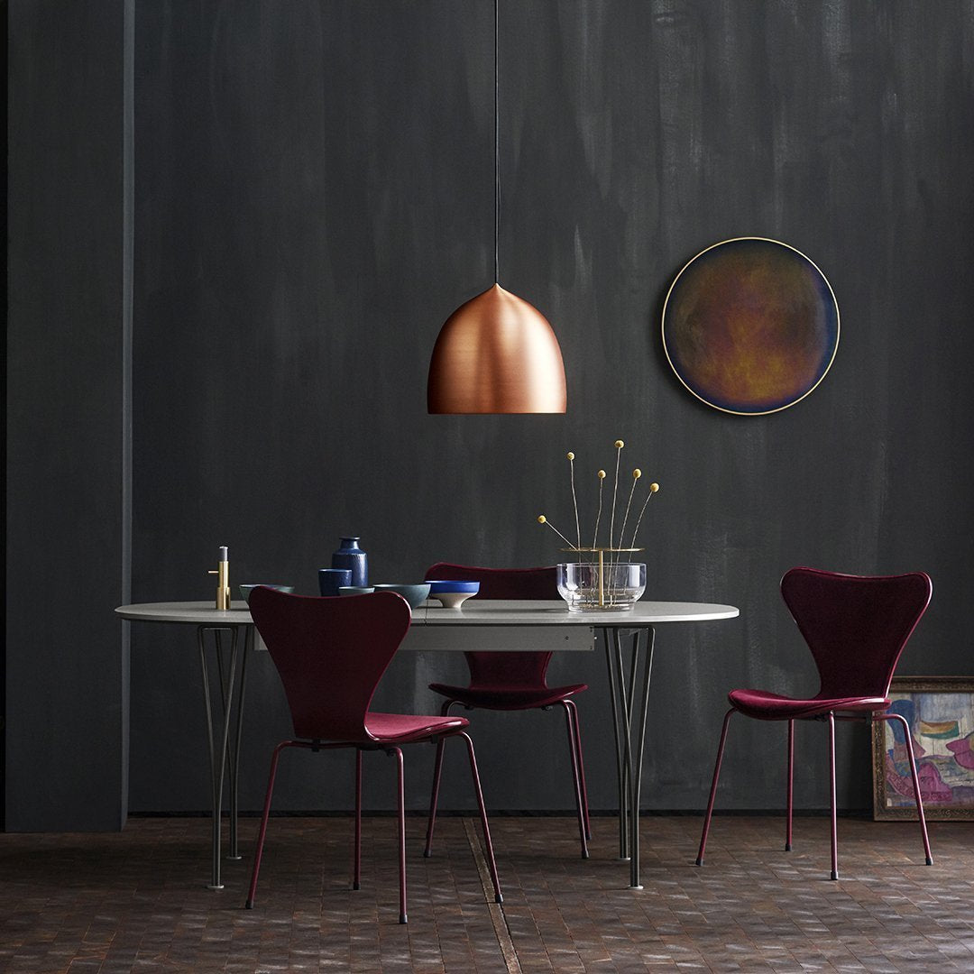 Modern dining set featuring deep burgundy chairs and a sleek white table, accented by a copper pendant light.