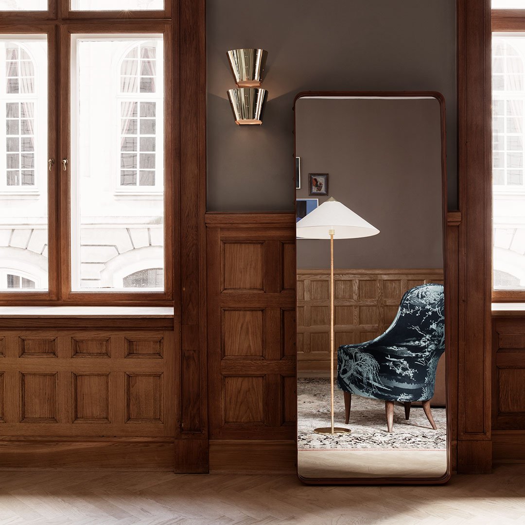 "Elegant floor mirror with a sleek frame, complemented by a textured blue chair and warm wooden accents."