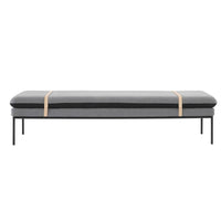 Gray and black padded bench with minimalist design and tan accent straps, set on a sleek black metal frame.