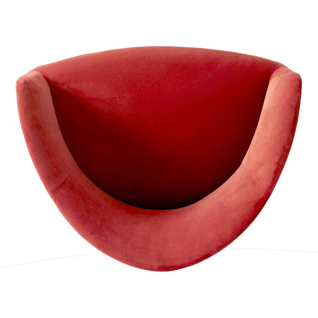 Red velvet curved chair with a smooth, plush finish, showcasing a modern design and vibrant color.