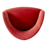 Red velvet curved chair with a smooth, plush finish, showcasing a modern design and vibrant color.