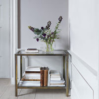 Elegant brass side table with glass top, featuring a sleek, minimalist design and neutral color palette.