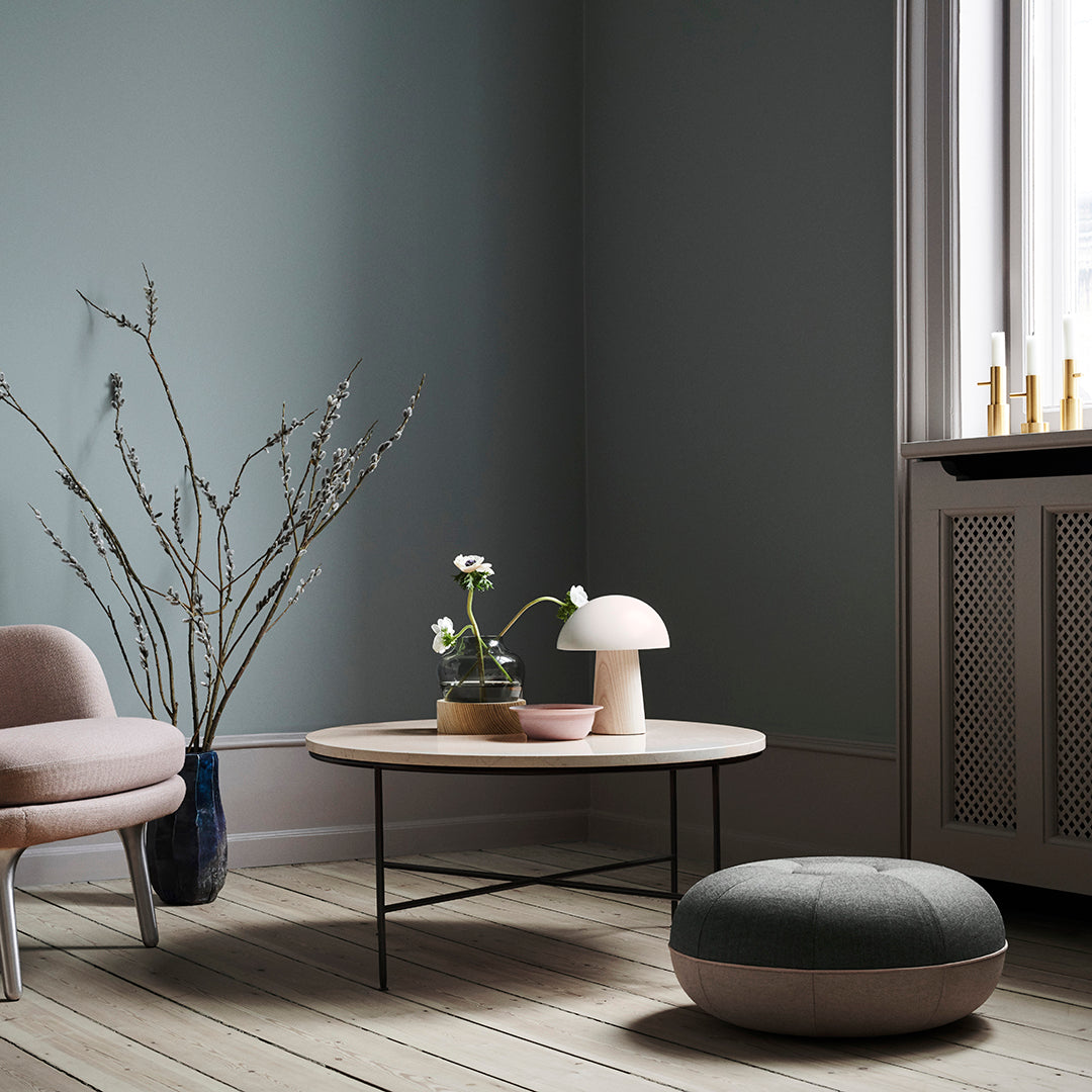 Soft blue-green wall, minimalist light wood flooring, pastel pink accents, and subtle gray patterns in soft furnishings.