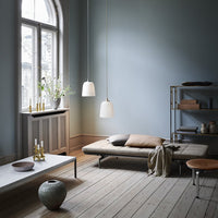 Soft blue walls, natural wood tones, beige textiles, and white pendant lights create a serene, modern interior.